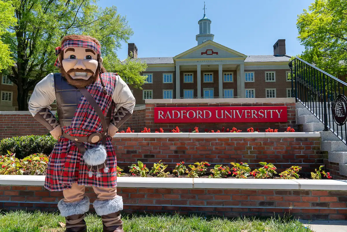 The Highlander mascot at the Radford University sign in front of Moffett Hall